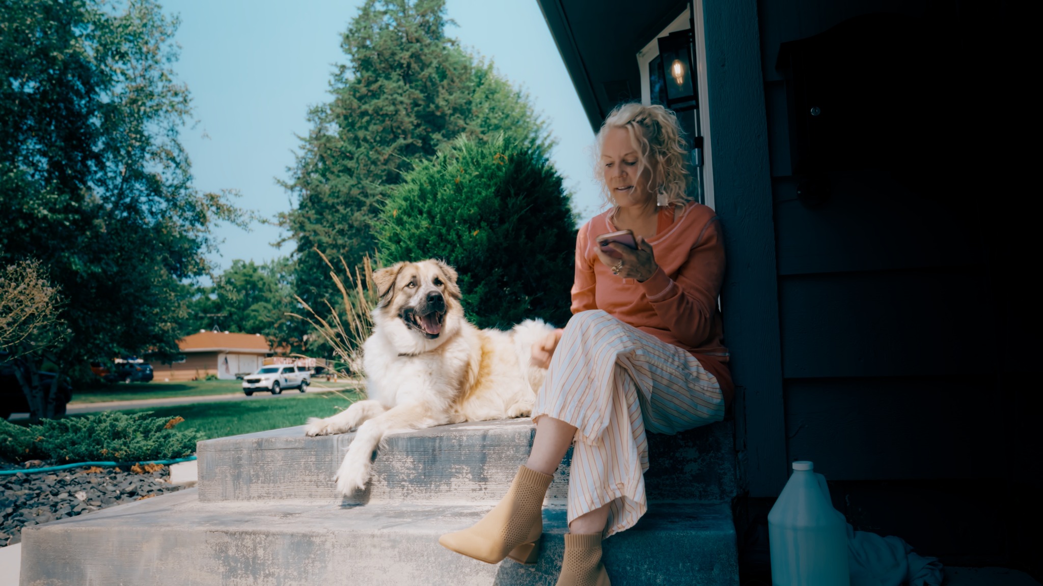Cyndi Dale seated on outdoor steps beside her dog.